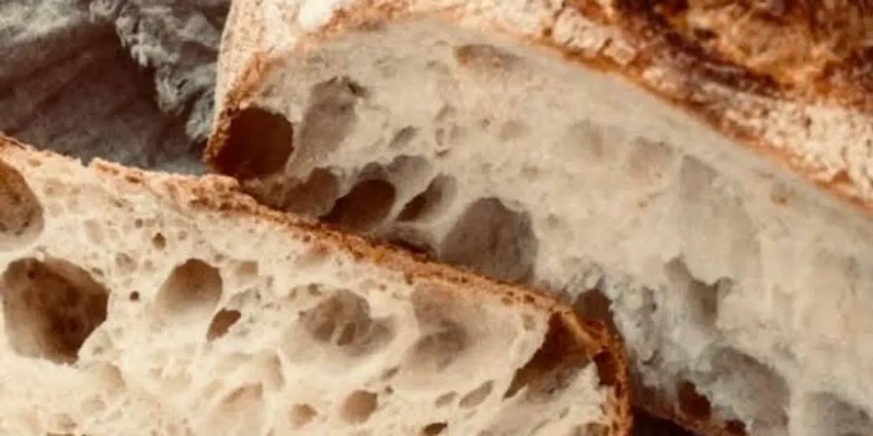 Close-up of rustic sourdough bread with airy crumb and crusty exterior.
