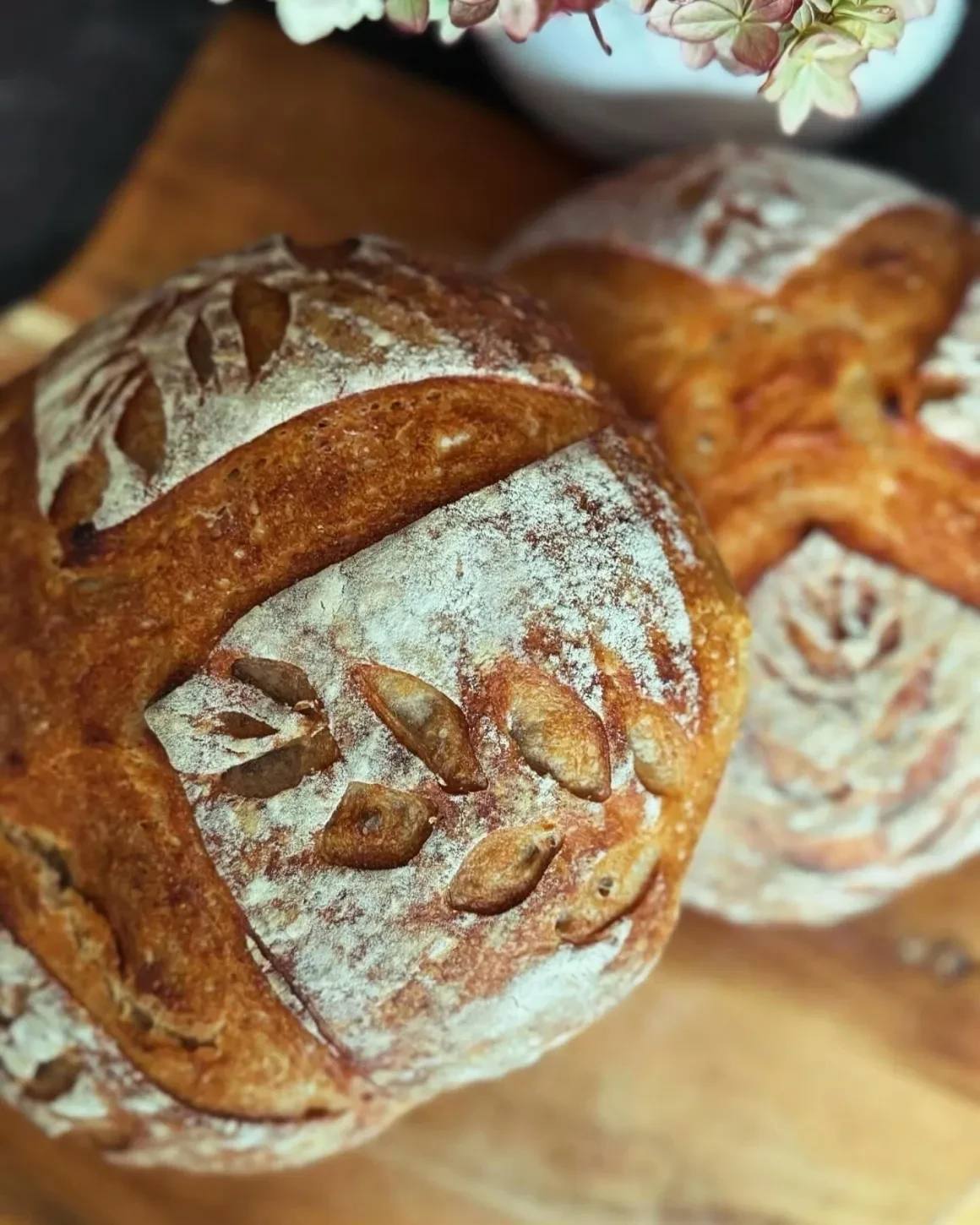 Two beautifully baked artisan sourdough loaves with decorative scoring.